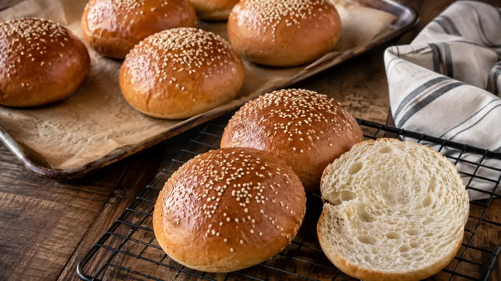 Buns maison dorés au sésame sortis du four, avec mie moelleuse visible sur une grille